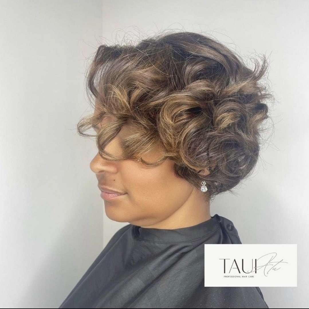 Curly pixie cut with warm caramel highlights styled at Taui Atu