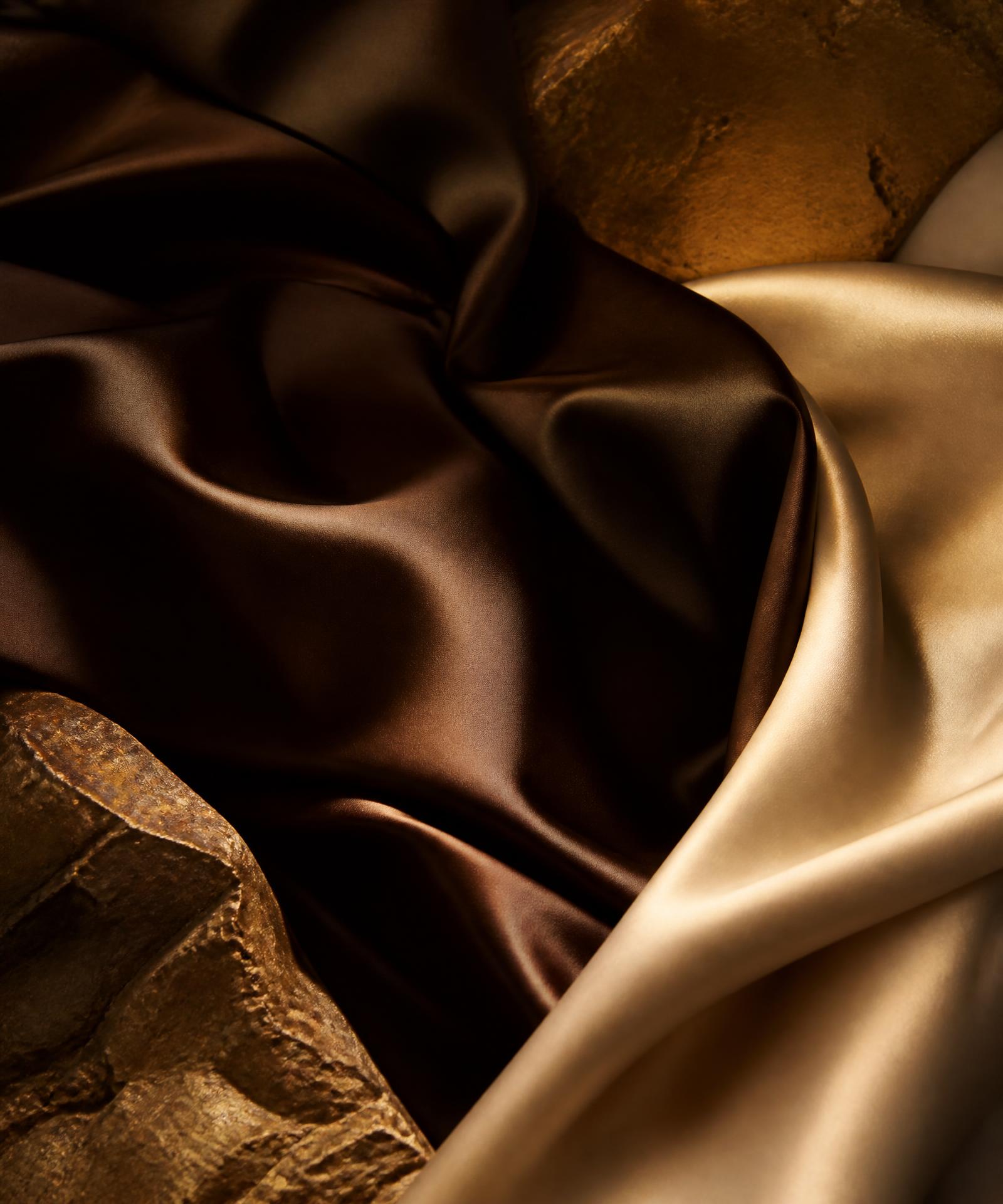 Abstract chocolate brown, gold, and ivory silk composition representing the Taui Atu brand